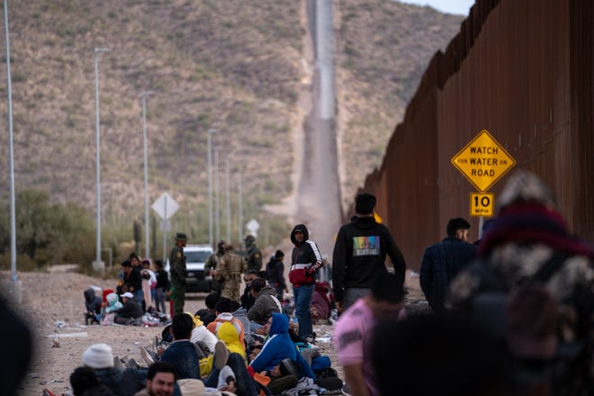 Migrants and asylum seekers wait to be picked up and processed by U.S. Border Patrol agents in Organ Pipe Cactus National Monument along the U.S.-Mexico border about a mile west of Lukeville, Ariz., on Dec. 4, 2023. The Lukeville Port of Entry was closed indefinitely by officials Dec. 4.