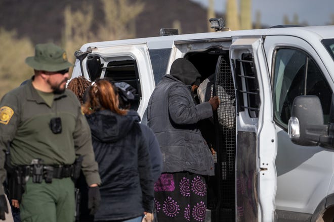 Migrants and asylum seekers are guided into vans to be transported for processing by U.S. Border Patrol agents in Organ Pipe Cactus National Monument along the U.S.-Mexico border about a mile west of Lukeville, Ariz., on Dec. 4, 2023. The Lukeville Port of Entry was closed indefinitely by officials Dec. 4.