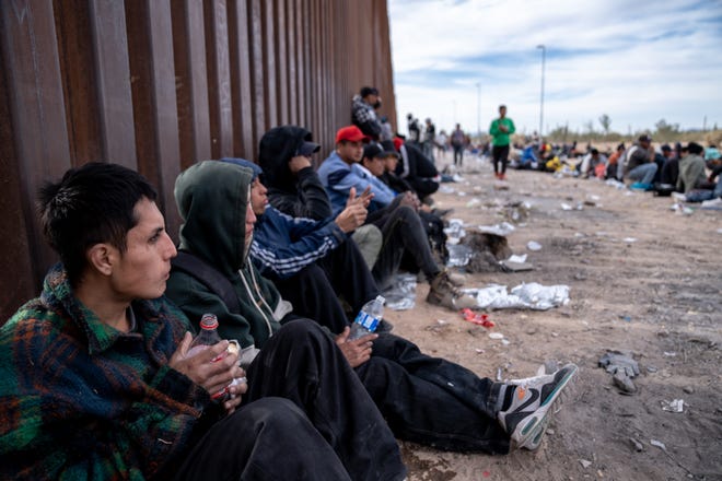 An asylum seeker from Ecuador waits with others to be picked up and processed by U.S. Border Patrol agents in Organ Pipe Cactus National Monument along the U.S.-Mexico border about a mile west of Lukeville, Ariz., on Dec. 4, 2023. The Lukeville Port of Entry was closed indefinitely by officials Dec. 4.