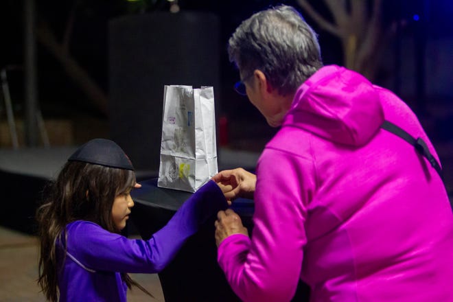 Judith Nichols teaches Elena Chen how to spin a dreidel at downtown Tempe's Menorah lightning on Dec. 7, 2023.