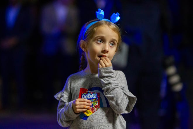 Shani Kripor's daughter Sarah eats dreidel candy at downtown Tempe's Menorah lightning on Dec. 7, 2023.