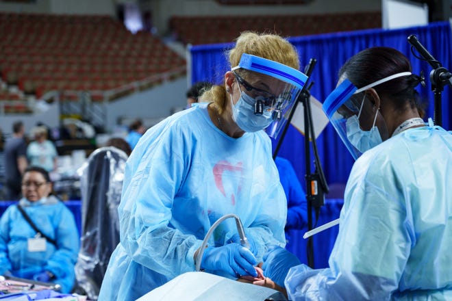 Dr. Dana Onet (left) and dental hygienist, Tabitha Blakley provide a filling for a patient during the Arizona Dental Mission of Mercy at the Veterans Memorial Coliseum on Dec. 8, 2023, in Phoenix.