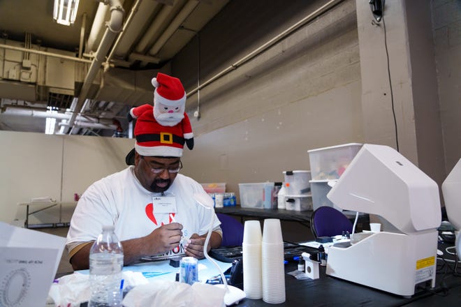 Lab technician, Kenneth Walker paints a dental stay plate for a patient during the Arizona Dental Mission of Mercy at the Veterans Memorial Coliseum on Dec. 8, 2023, in Phoenix. Stay plates, among other services, are provided free of charge at this annual event.