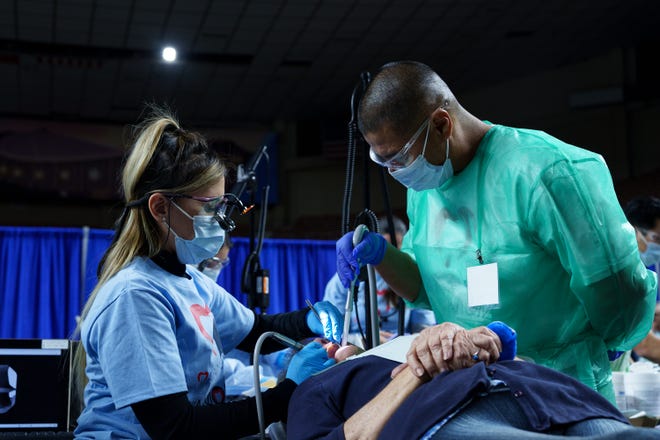 Dr. Margaret Tran (left) and dental assistant, Rojelio Favela work on a filling for Darlene Layton during the Arizona Dental Mission of Mercy at the Veterans Memorial Coliseum on Dec. 8, 2023, in Phoenix. Fillings, among other services, are provided free of charge at this annual event.