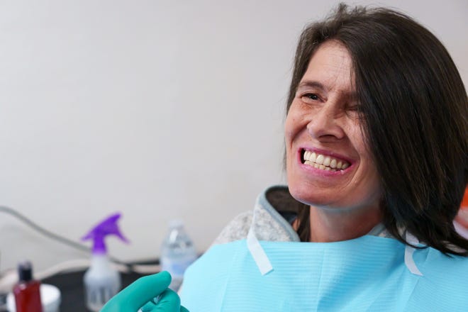 Susan Zygutis smiles to show the fit of her new dentures to the dentist as she receives care at the Arizona Dental Mission of Mercy at the Veterans Memorial Coliseum at the Arizona State Fairgrounds on Dec. 8, 2023, in Phoenix.